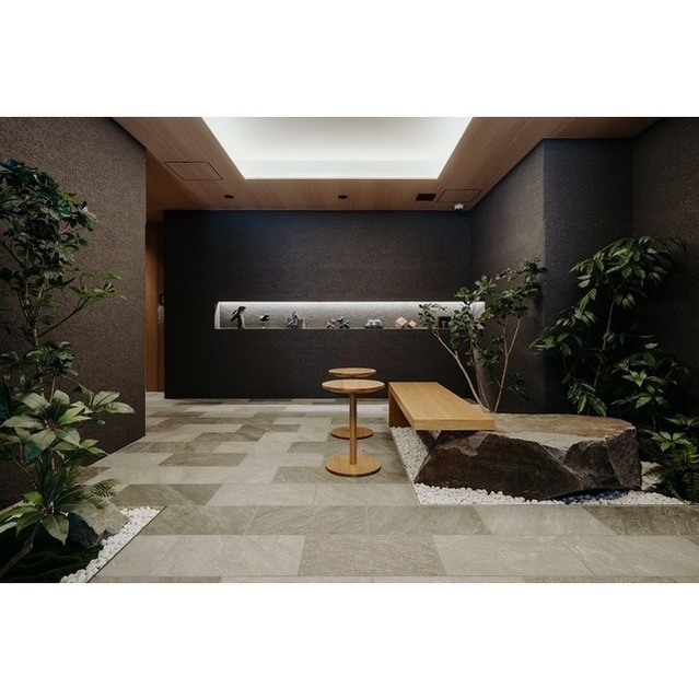 エントランスホール。石張りの床と植栽、ベンチを配した空間